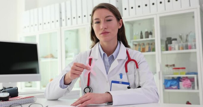 Female gynecologist doctor holds pink ribbon as symbol of breast cancer awareness