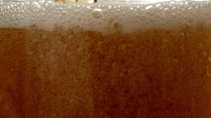 Pouring beer into glass. Closeup slow motion shot. Bubbles rising up stream of a