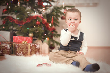 Little boy at time of christmas day unpacking gifts near tree
