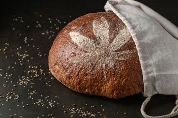 Fresh baked loaf of spelt bread with crushed hemp seeds. Bread decorated with cannabis leaf made of...
