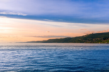 scenic sea shore view of island in ocean with waves and amazing cloudy sunset or sunrise on backgeound, vacation landscape of rocky beautiful isle