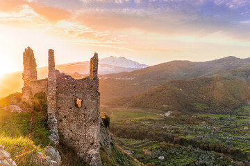 beautiful sunset or sunrise landscape of ancient ruins on a top of a hill with green mountains with...