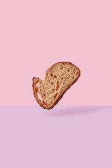 Slice of  brown Bread Flying over Pink and Purple Background