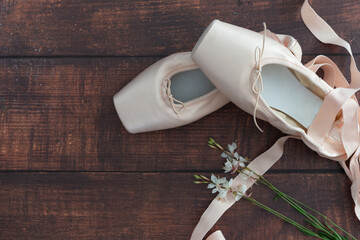 simple composition of satin dance slippers on a wooden floor and jasmine flowers to celebrate the...