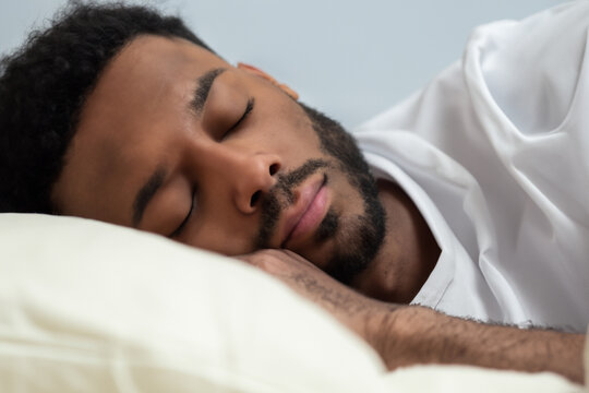 the man is sleeping. young afro man in a white tank top sleeping on his bed, quiet time, close-up view, sleep concept