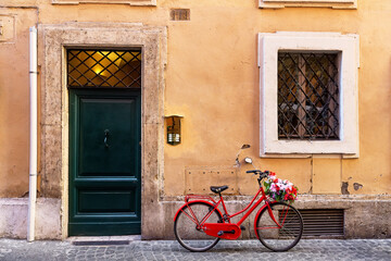 Fototapeta na wymiar Image of a red bicycle on an old narrow cobblestone street in Rome, Italy.