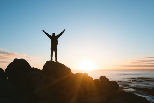 Homme au sommet d'une montagne levant les bras. Man on top of a mountain raising his arms.