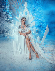 Art photo real people Fantasy woman snow queen sits on ice throne, white long dress cape bird...