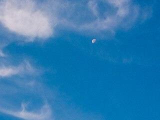 Beautiful blue sky with white clouds and the moon like a small ball