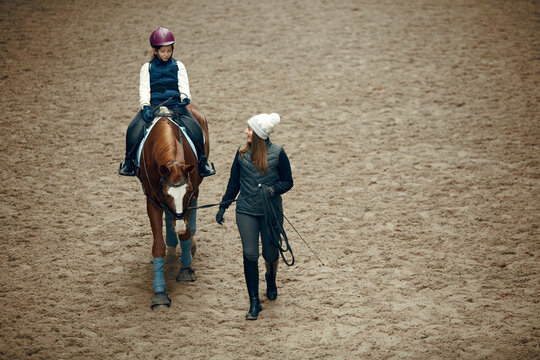 Aerial, top view. Female teacher, instructor teaching little girl, kid horseback riding. Careful ride, outdoor lesson. Sport, childhood, school and educational course, active lifestyle, hobby concept