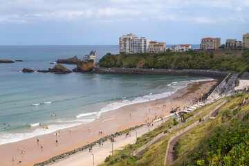 Biarritz, France. Panoramic view of the beach with surfers, walking embankment and scenic rocky coastline.