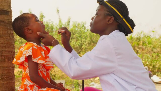 Otorhinolaryngology Female doctor in africa checking throat of young black children patient in small clinic hospital village 
