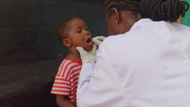 Africa nurse doctor collecting saliva sample from black african children in clinic hospital for diagnosis exam disease prevention africa healthcare medical system 