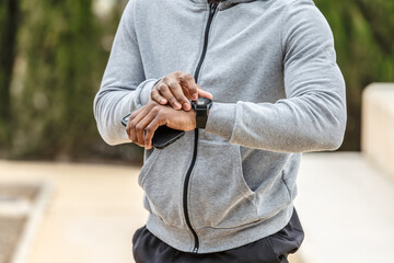 Crop black male athlete checking heartbeat on tracker