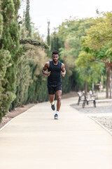 African American sportsman in activewear jogging along park during morning exercise