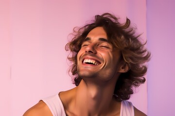 An exuberant male model laughing heartily against a soft lavender pink background.