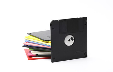 Black and stack of colored floppy disks on white background