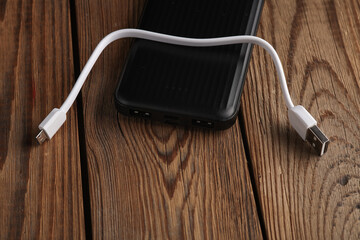 Power bank with cable on wooden table