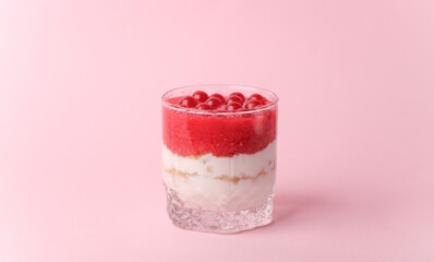 Homemade layered Dessert in a glass cup with yogurt and berries on a pink background