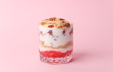 Homemade layered Dessert in a glass cup with yogurt and cookie on a pink background