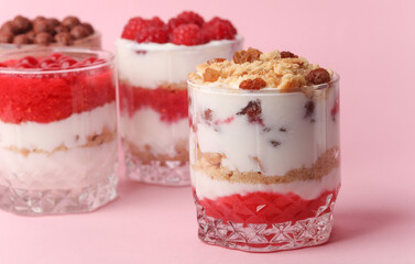 Homemade layered Desserts in a glass cups with yogurt, berries, cookie and chocolate on a pink background