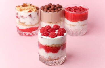 Homemade layered Desserts in a glass cups with yogurt, berries and chocolate on a pink background