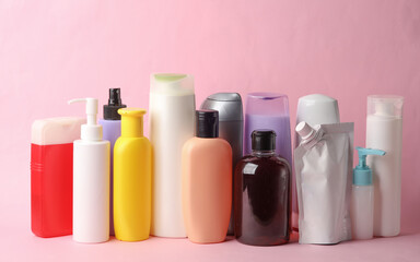 Many different shampoo and other cosmetic product bottles on pink background