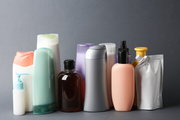 Different shampoo and other cosmetic product bottles on dark gray background - obrazy, fototapety, plakaty