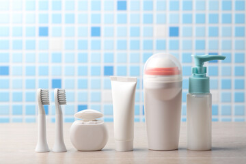 Toothbrush heads, dental floss, tube of toothpaste, liquid soap, antiperspirant on the table. Personal hygiene products