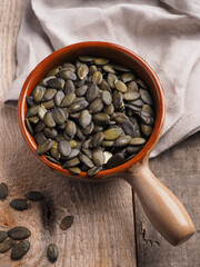 Tasty organic pumpkin seeds in a ceramic bowl on a wooden kitchen table