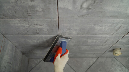 Close-up of grouting tiles in a bathroom. Close-up of the grouting process, on the wall tile with a...