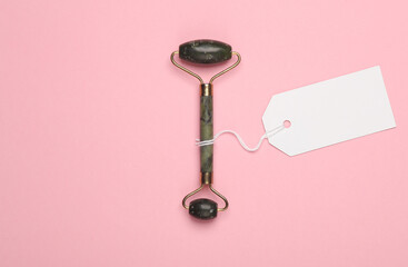 Jade massage roller with price tag on pink background