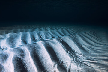 Tropical clear blue ocean  with sand bottom on night. Underwater view with artificial light