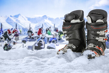 Ski boots on snow and winter landscape of mountains. 