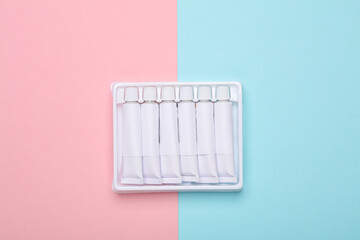 Set of white empty tubes of acrylic or oil paint for creativity on pink blue background. Template for design, mockup