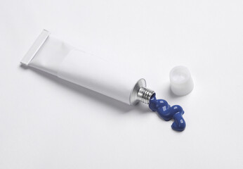 White empty tube of blue acrylic or oil paint for creativity on white background. Template for design, mockup