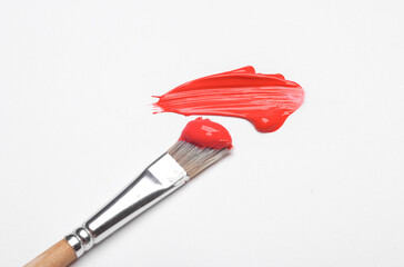 Smear of red acrylic paint and brush on a white background