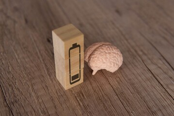Closeup image of brain and wooden blocks with low energy battery icon. Exhausted, tired and burnout...