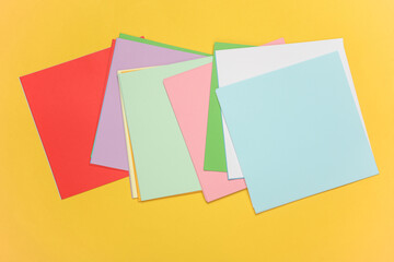 Square sheets of paper for origami creativity on yellow background