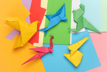 Paper folded origami animal figurines on colored sheet of papers. Hobbies, creativity - obrazy, fototapety, plakaty