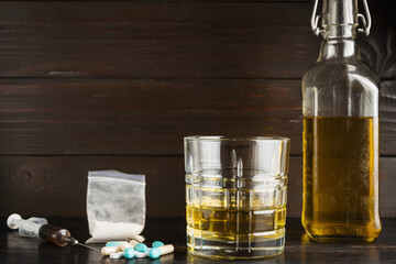 Alcohol drink in a glass, pills, syringe with drug substance, heroin dose, narcotics powder in...