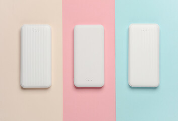 White power banks on pastel background. External batteries for charging smartphone and other gadgets. Top view