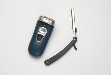 Electric razor and straight razor on white background