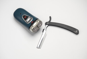 Electric razor and straight razor on white background