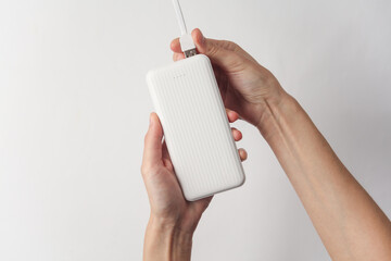 Hands holding white external battery power bank on white background - obrazy, fototapety, plakaty