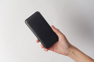 Hands holding black external battery power bank on white background