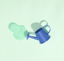 Creative minimalist layout. Watering can with slime on blue background. Surreal summer idea. Conceptual pop