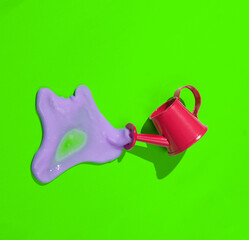 Creative minimalist layout. Watering can with slime on a green background. Surreal summer idea. Conceptual pop