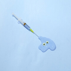 Creative medicine layout. Syringe with slime and eyes on blue background. Surreal idea. Conceptual pop