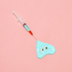 Creative medicine layout. Syringe with slime and eyes on pink background. Surreal idea. Conceptual pop